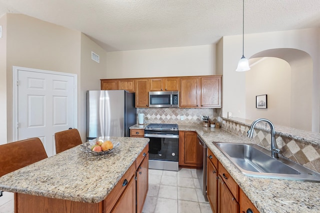 kitchen featuring hanging light fixtures, sink, appliances with stainless steel finishes, and a textured ceiling