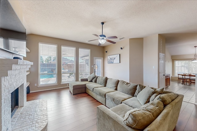 living room featuring a wealth of natural light, ceiling fan, a textured ceiling, and hardwood / wood-style flooring