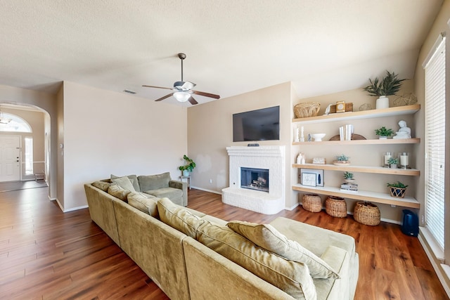 living room featuring hardwood / wood-style flooring, a brick fireplace, ceiling fan, and a healthy amount of sunlight