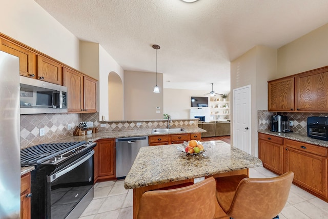 kitchen featuring a kitchen bar, appliances with stainless steel finishes, sink, pendant lighting, and a center island