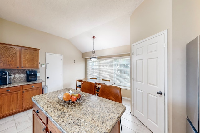 kitchen with light tile patterned floors, vaulted ceiling, a kitchen island, and hanging light fixtures