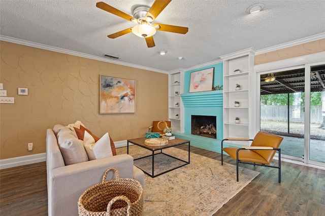 living room with built in shelves, ceiling fan, dark hardwood / wood-style floors, a textured ceiling, and ornamental molding