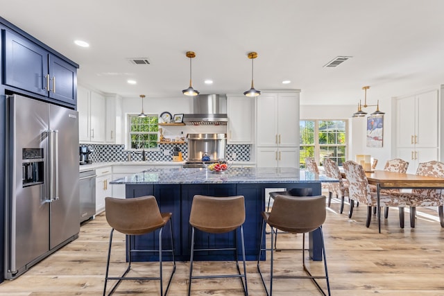 kitchen featuring appliances with stainless steel finishes, pendant lighting, white cabinetry, and a kitchen island