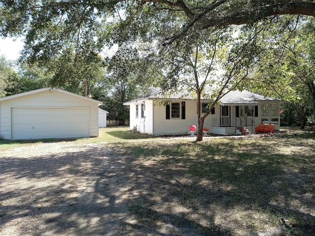 single story home featuring a garage, covered porch, and an outbuilding