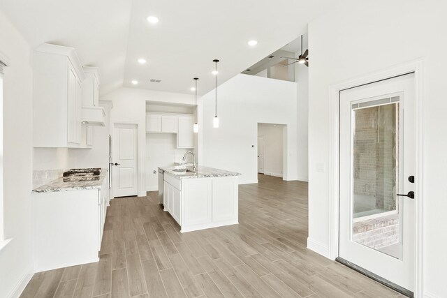 kitchen with decorative light fixtures, a towering ceiling, sink, and light stone counters