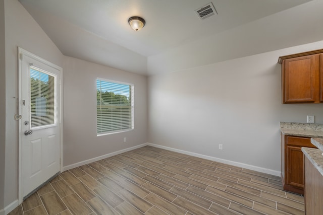 unfurnished dining area featuring light wood-type flooring and vaulted ceiling