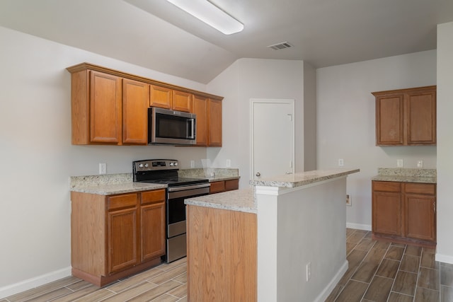 kitchen featuring a center island, vaulted ceiling, appliances with stainless steel finishes, light stone counters, and wood-type flooring