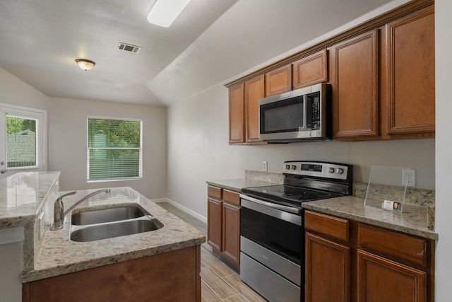 kitchen featuring light stone counters, sink, stainless steel appliances, and a wealth of natural light