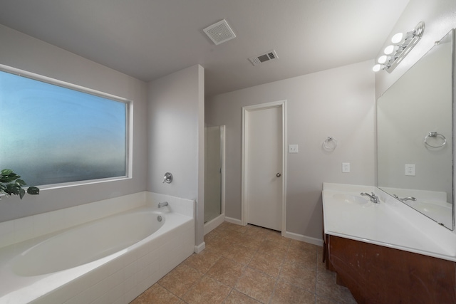 bathroom featuring plus walk in shower, vanity, and tile patterned flooring