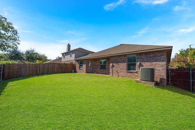 rear view of house featuring central AC unit and a yard