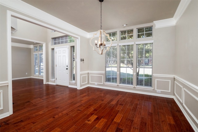 unfurnished dining area featuring dark hardwood / wood-style floors, ornamental molding, and a notable chandelier