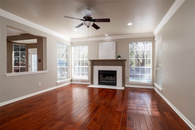 unfurnished living room featuring a tile fireplace, dark hardwood / wood-style floors, ceiling fan, and ornamental molding