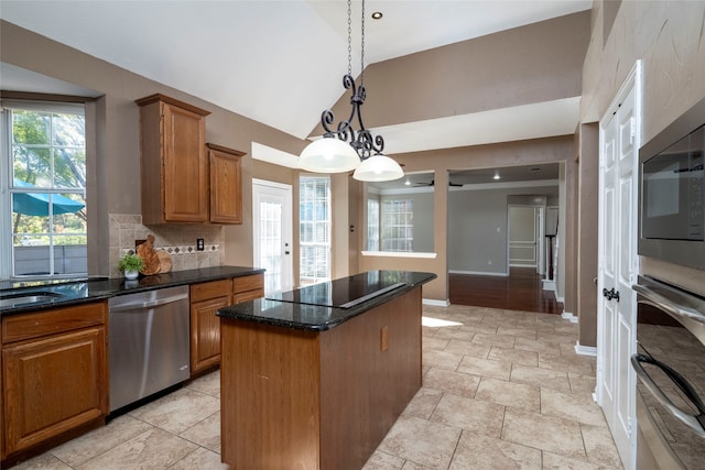 kitchen featuring hanging light fixtures, high vaulted ceiling, dark stone countertops, a kitchen island, and appliances with stainless steel finishes