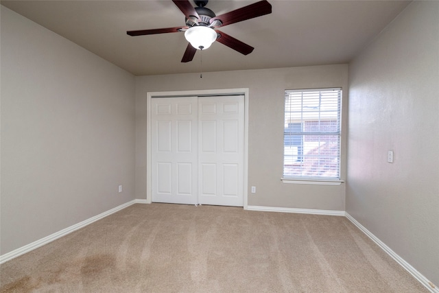 unfurnished bedroom featuring ceiling fan, a closet, and light colored carpet