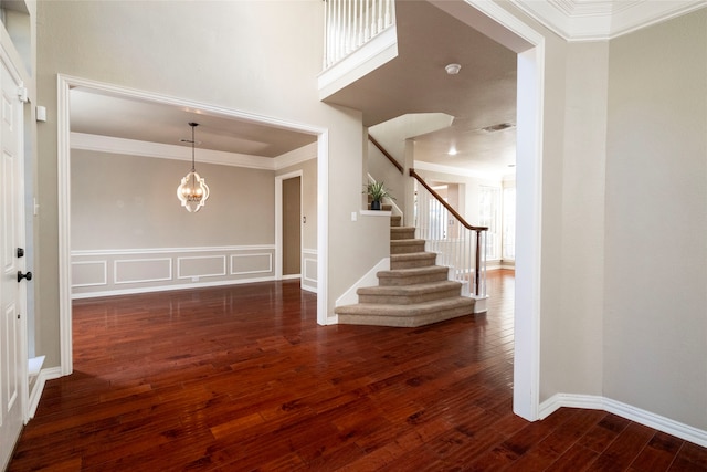 foyer featuring ornamental molding, dark hardwood / wood-style floors, and an inviting chandelier