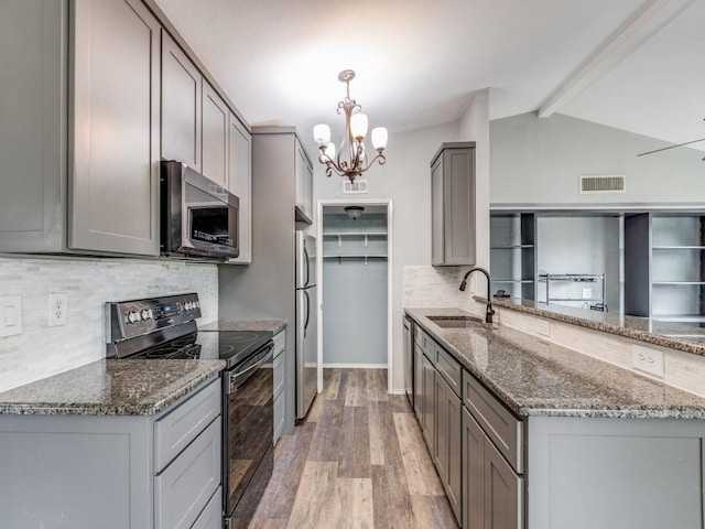 kitchen featuring sink, an inviting chandelier, vaulted ceiling with beams, light hardwood / wood-style flooring, and appliances with stainless steel finishes