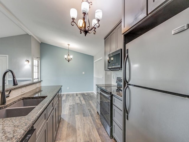 kitchen with a chandelier, stainless steel appliances, lofted ceiling, and sink