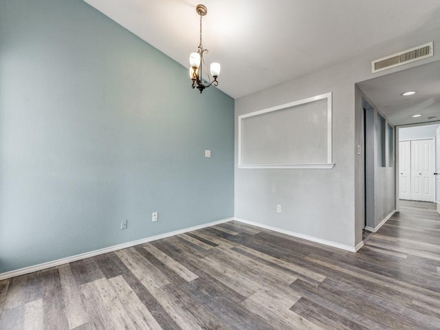 unfurnished room with dark hardwood / wood-style flooring and an inviting chandelier