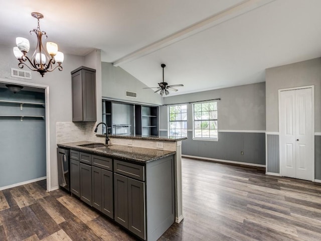 kitchen with gray cabinets, dark stone countertops, kitchen peninsula, and sink