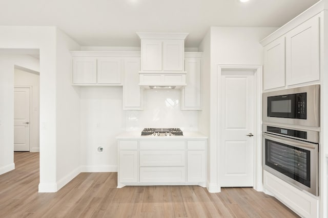 kitchen with decorative backsplash, light hardwood / wood-style floors, stainless steel appliances, and white cabinets