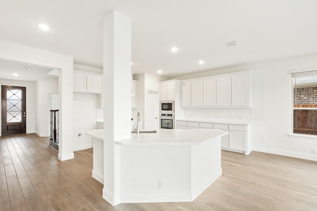 kitchen featuring light hardwood / wood-style floors, white cabinetry, sink, and oven