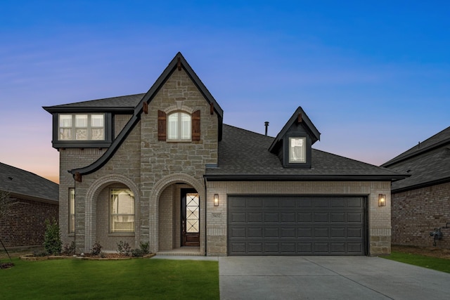 french country style house featuring a garage and a lawn