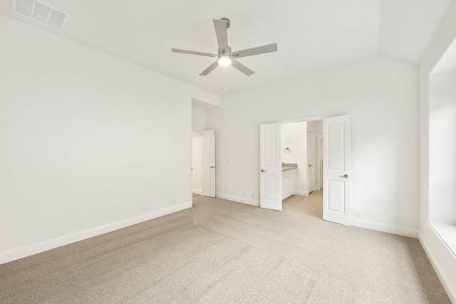 spare room with light carpet, vaulted ceiling, ensuite bathroom, and ceiling fan