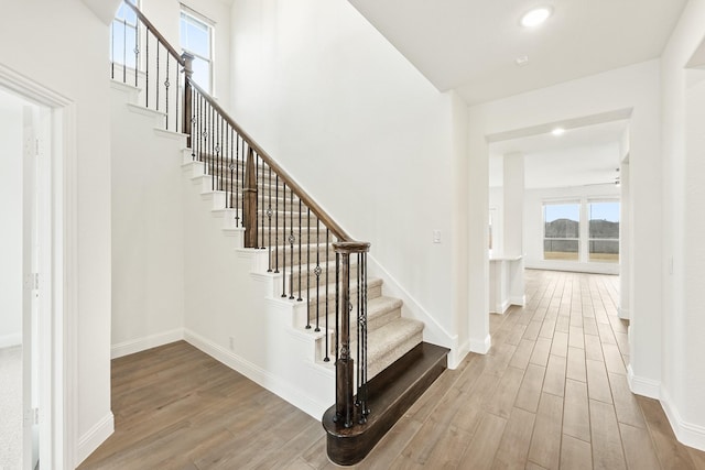 stairs featuring hardwood / wood-style floors and a towering ceiling