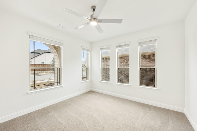 carpeted empty room with a wealth of natural light and ceiling fan