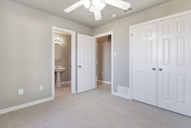 unfurnished bedroom featuring ceiling fan, a closet, ensuite bathroom, and light carpet