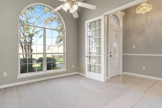 tiled entrance foyer featuring ceiling fan with notable chandelier