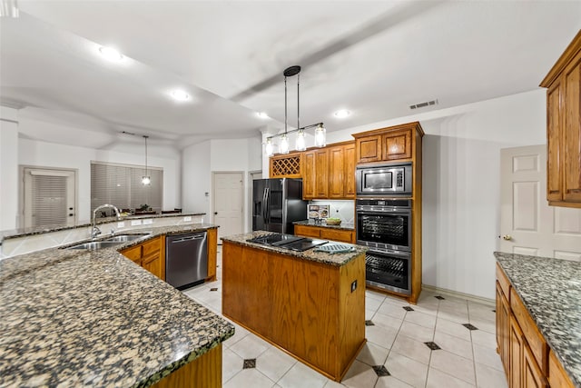 kitchen featuring sink, a kitchen island, appliances with stainless steel finishes, dark stone counters, and decorative light fixtures