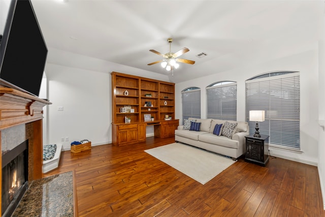 living room with a fireplace, dark hardwood / wood-style flooring, and ceiling fan