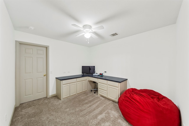 carpeted home office featuring built in desk and ceiling fan