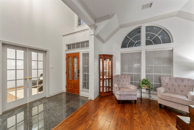 foyer with dark hardwood / wood-style flooring, high vaulted ceiling, french doors, and ornamental molding