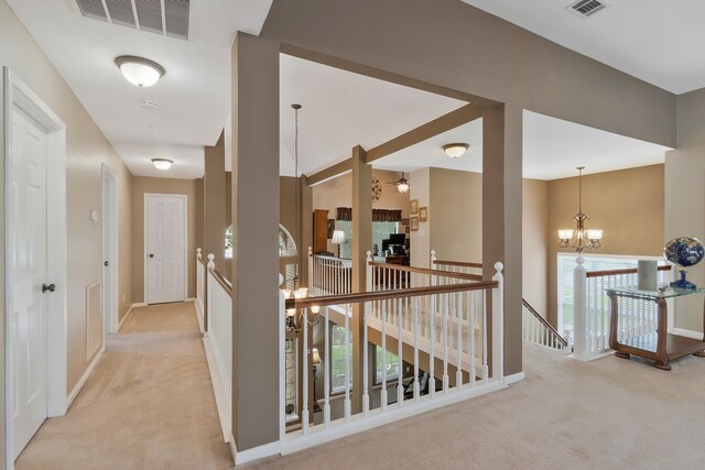 hall with a notable chandelier, light carpet, and plenty of natural light