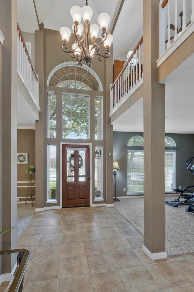 carpeted foyer with a high ceiling, an inviting chandelier, and plenty of natural light