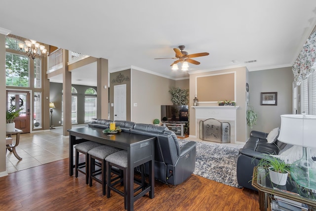 living room featuring crown molding, dark hardwood / wood-style floors, and ceiling fan with notable chandelier