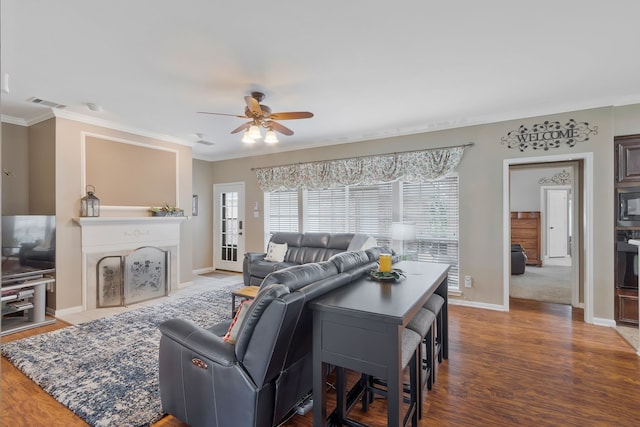 living room featuring ceiling fan, ornamental molding, and hardwood / wood-style flooring