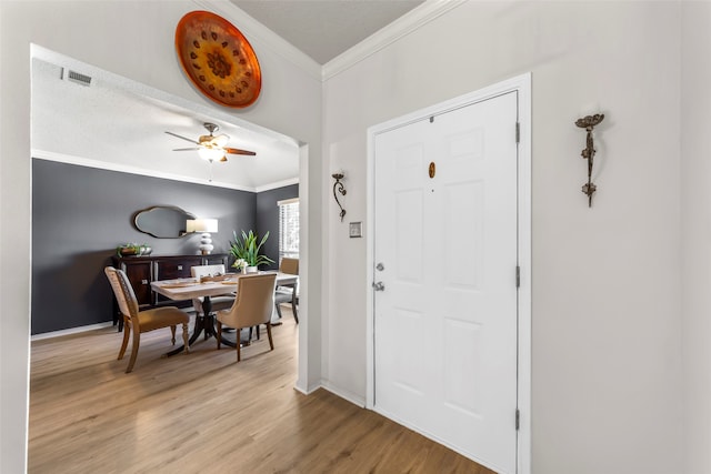 entryway with ceiling fan, crown molding, and light hardwood / wood-style floors