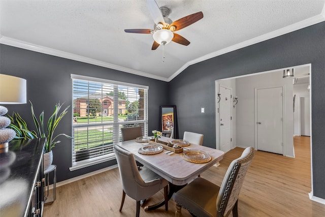 dining space with vaulted ceiling, ornamental molding, ceiling fan, and light wood-type flooring