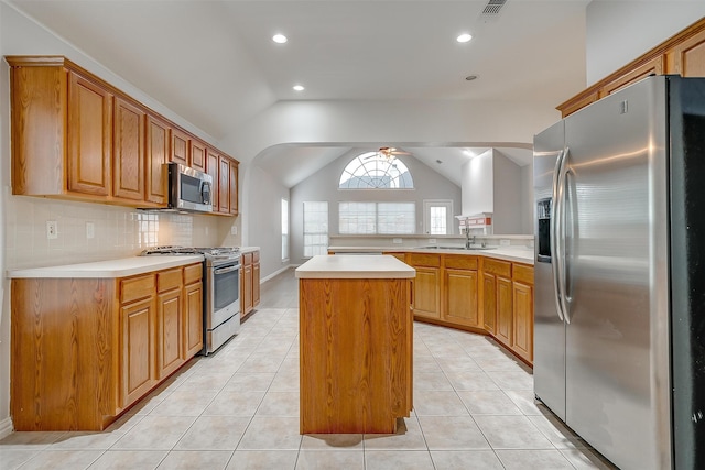 kitchen featuring kitchen peninsula, appliances with stainless steel finishes, light tile patterned floors, a center island, and lofted ceiling