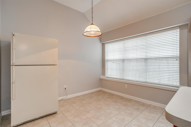 unfurnished dining area featuring light tile patterned floors and vaulted ceiling