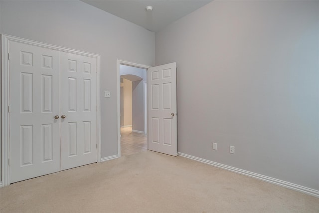 unfurnished bedroom featuring light carpet and a closet