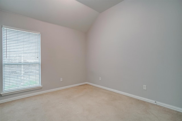 carpeted empty room featuring lofted ceiling