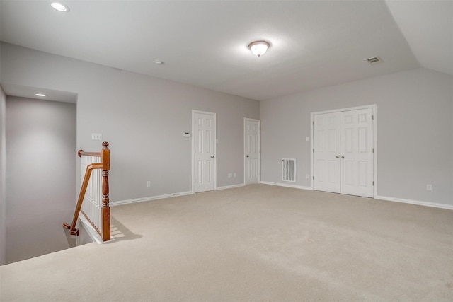 carpeted empty room with lofted ceiling