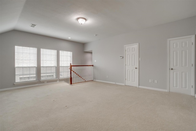 carpeted empty room with lofted ceiling