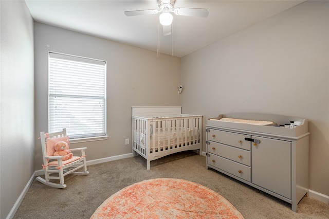 bedroom featuring ceiling fan, light colored carpet, and a crib