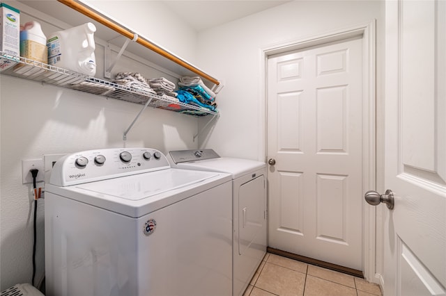 clothes washing area with washing machine and dryer and light tile patterned floors