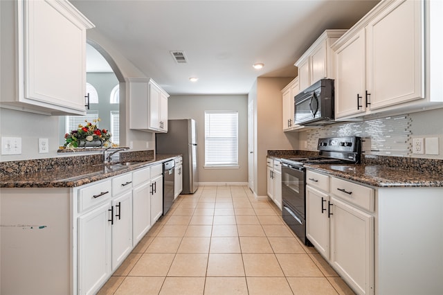 kitchen featuring sink, light tile patterned floors, dark stone countertops, white cabinets, and black appliances